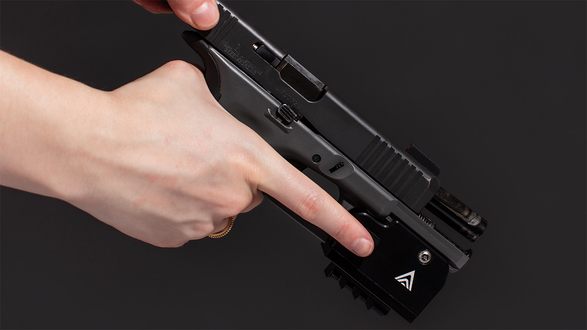 Person holding a pistol with a B.O.S. Lock biometric lock attached